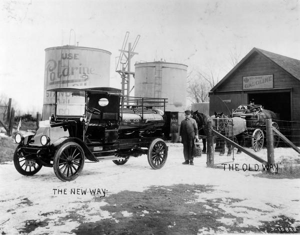 Man standing on snow-covered ground with an International Model G truck and horse-drawn wagon at an oil depot. Handwritten captions on the photo mark "the new way" and "the old way" of transporting oil. A large oil tank advertises "Polarine Oil." The truck was owned by the Standard Oil Company.
