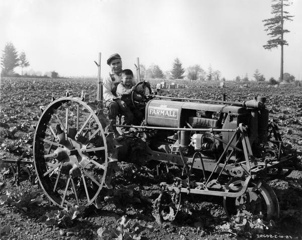 Farmer Sam Tanaka posing with his son on a Farmall F-12 tractor in a cauliflower field.