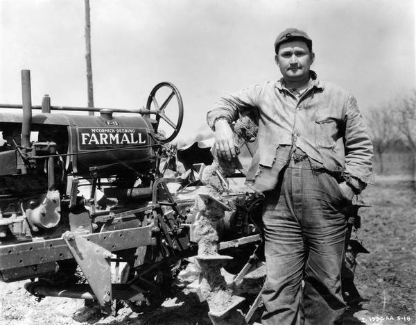 Farmer poses with a Farmall F-12 tractor with #90 plow.