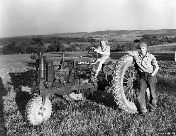 Beverly Lundsten and hired man Gerald Stanford pose with a Farmall F-12 tractor on the Lundsten farm. The tractor is equipped with rubber tires and a single front wheel.