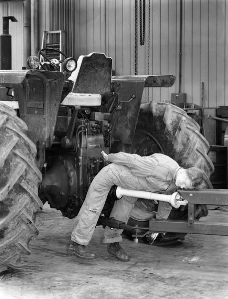Dummy straddling the rear drive shaft of an International Harvester tractor in a demonstration of the hazards of carelessness.