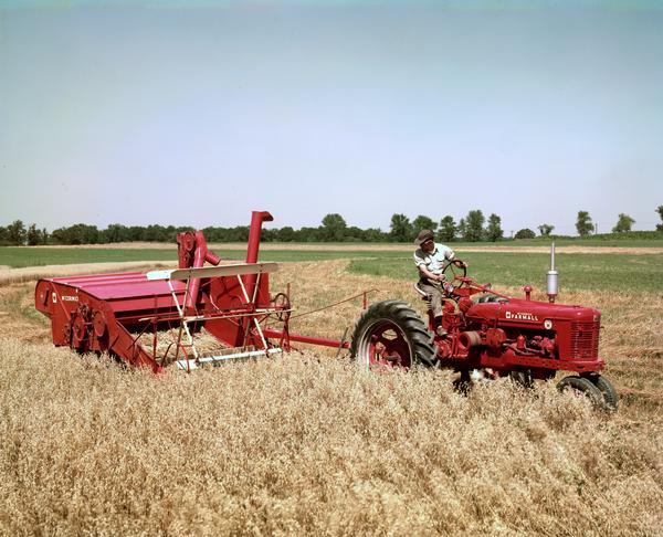 Farmer harvesting grain with a Farmall Super H tractor and No. 64 combine.