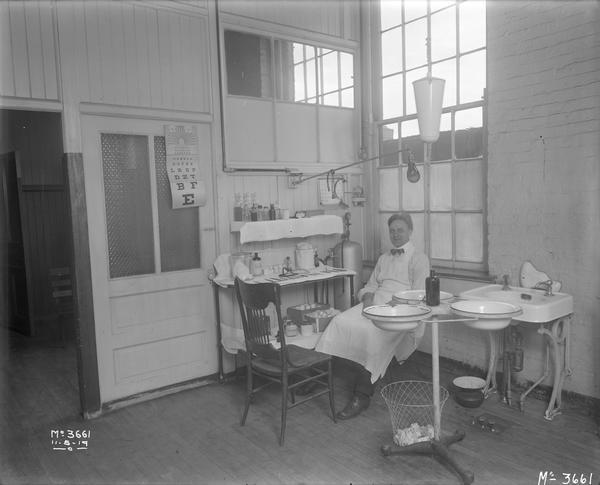 Factory doctor sitting in a doctor's office or first aid station at International Harvester's McCormick Works.