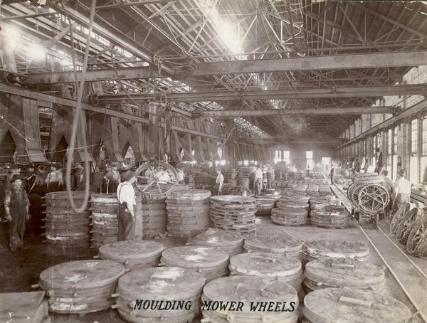 Workers removing mower wheels from casts inside Foundry no. 1 at the McCormick Reaper Works. The factory was owned by the McCormick Harvesting Machine company before 1902. In 1902 it became the McCormick Works of the International Harvester Company. The factory was located at Blue Island and Western Avenues in the Chicago subdivision called "Canalport". It was closed in 1961.