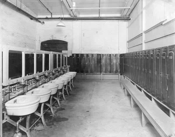 Locker room at International Harvester's Osborne Works. Lockers and benches line two walls and a row of sinks or wash basins with mirrors line a third. The Osborne Works was owned by the D.M. Osborne Company until 1903, when it was purchased by International Harvester. The factory was later known within the company as the "Auburn Works." It was located at 5 Pulaski Street.