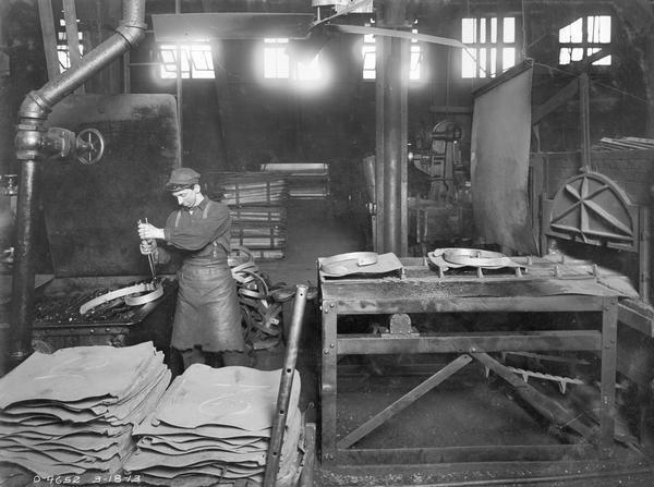 Factory worker preparing a harrow spring tooth for a heat treating furnace at International Harvester's Osborne Works.
