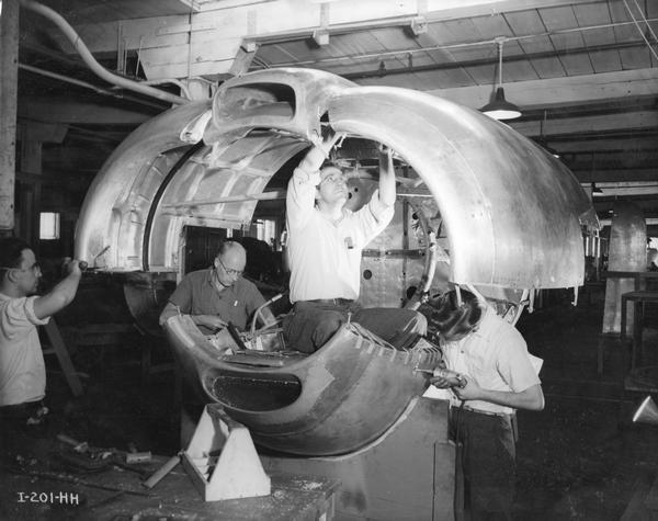 Factory workers assembling an engine cowling for the Curtiss-Wright C-46 Commando cargo and transport airplane during World War II at International Harvester's Auburn Works. The factory was owned by the D.M. Osborne Company until 1903, when it was purchased by International Harvester. It was initially known as the "Osborne Works" and later became known within the company as the "Auburn Works."