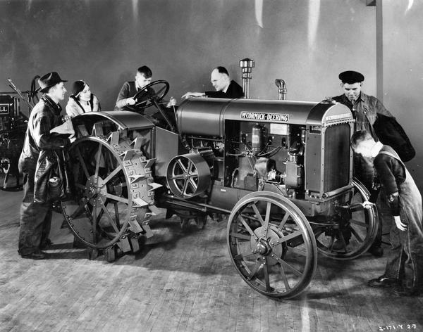 Salesman showing a new McCormick-Deering W-30 tractor to a small group of men, women, and children in the showroom of an International Harvester dealership. The photograph appears to have been "touched up" for advertising purposes.
