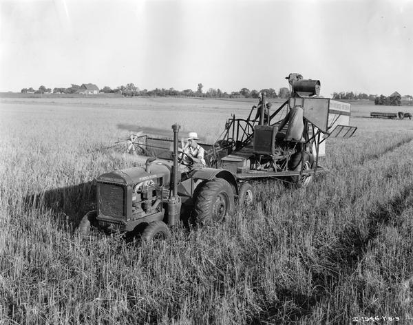 Slightly elevated view of men harvesting wheat with a McCormick-Deering Model W-30 tractor and a Model 8 combine (harvester-thresher) equipped with an auxiliary engine. The tractor and combine were owned by George Todd and were equipped with Firestone tires.