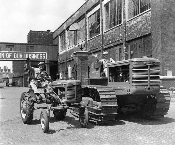 Two workers wave from the seats of a Farmall A tractor and an International TD-18 diesel crawler tractor (TracTracTor) outside International Harvester's Tractor Works.