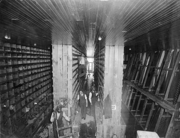 Elevated view of factory workers standing between rows of parts bins at International Harvester's McCormick Works. The factory was owned by the McCormick Harvesting Machine Company before 1902.