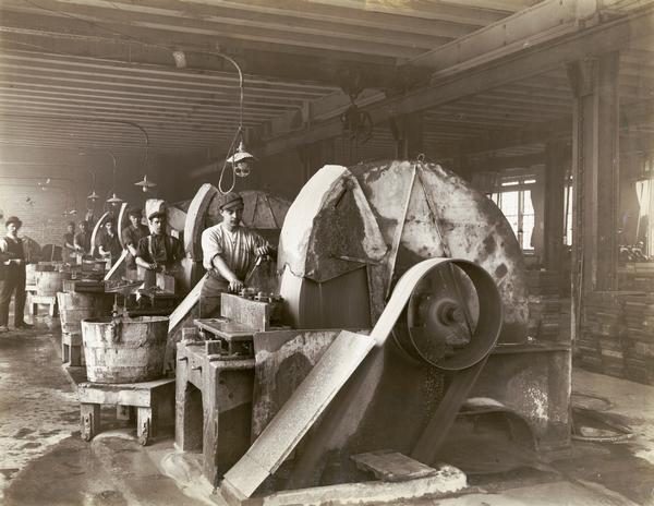Factory workers operating large industrial grinders at International Harvester's Hamilton Works in Hamilton, Ontario, Canada.