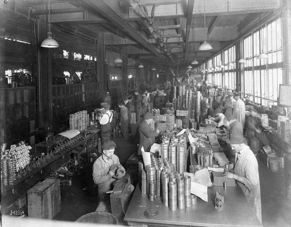 Elevated view of factory workers handling tractor parts at International Harvester's Tractor Works. The factory was in operation from 1910-1972 and was located at 2600 West 31st Blvd.