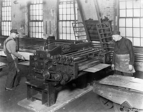 Factory workers cutting pieces of sheet metal at Internaitonal Harvester's Deering Works. The factory was owned by the Deering Harvester Company before 1902, and was located at Fullerton and Clybourn Avenues.