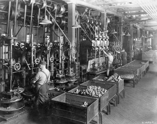 Factory workers drilling(?) parts at International Harvester's Deering Works. The factory was owned by the Deering Harvester Company before 1902, and was located at Fullerton and Clybourn Avenues.