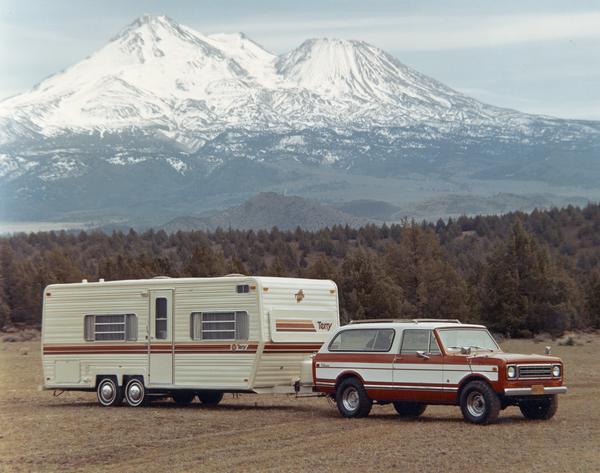 Color advertising photograph of a 1977 International Scout Traveler pickup with Terry camper set against a mountainous backdrop.
