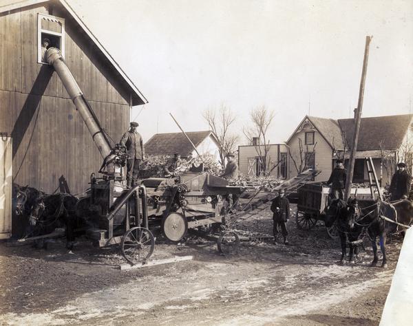 Men are posing with a McCormick-Deering 8-roll husker and shredder owned by the Wild Creek Threshing Company.