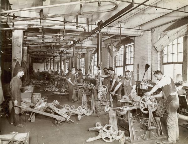 Workers assembling mowers in the Mower Room of the McCormick Reaper Works. The factory was owned by the McCormick Harvesting Machine company before 1902. In 1902 it became the McCormick Works of the International Harvester Company. The factory was located at Blue Island and Western Avenues in the Chicago subdivision called "Canalport." It was closed in 1961.