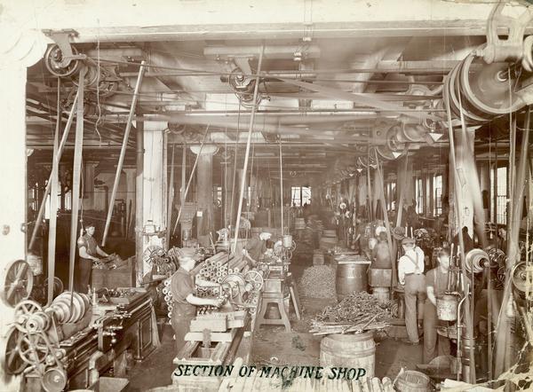 Workers machining parts with belt-driven lathes, presses, and other machinery in a machine shop at McCormick Reaper Works. The factory was owned by the McCormick Harvesting Machine company before 1902. In 1902 it became the McCormick Works of the International Harvester Company. The factory was located at Blue Island and Western Avenues in the Chicago subdivision called "Canalport". It was closed in 1961.