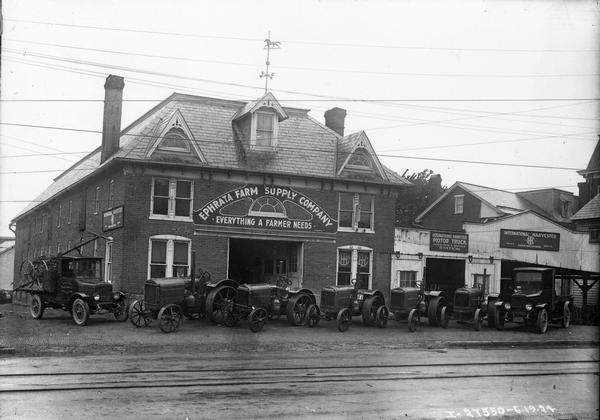 McCormick-Deering tractors (including the 10-20)  and two International trucks parked in front of the Ephrata Farm Supply Company, an International Harvester agricultural equipment dealership.