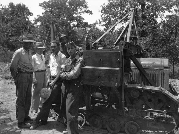 Five men are standing with a McCormick-Deering crawler tractor (TracTracTor) during a construction project.