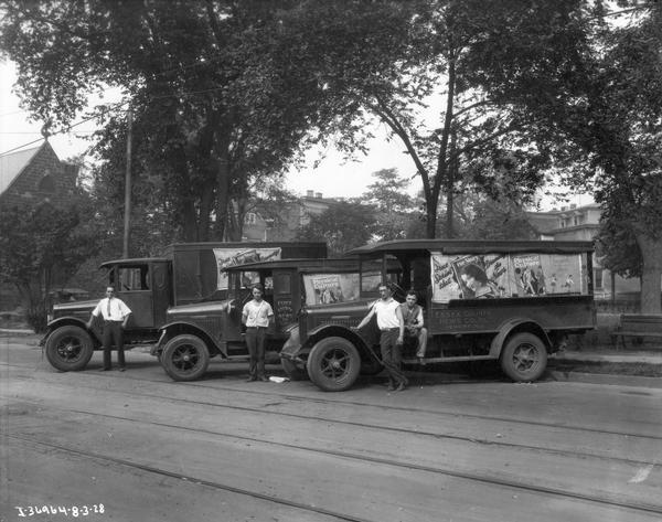 Four delivery drivers posing with three International trucks carrying publications (including "True Story") of the Essex County News Co., Inc.