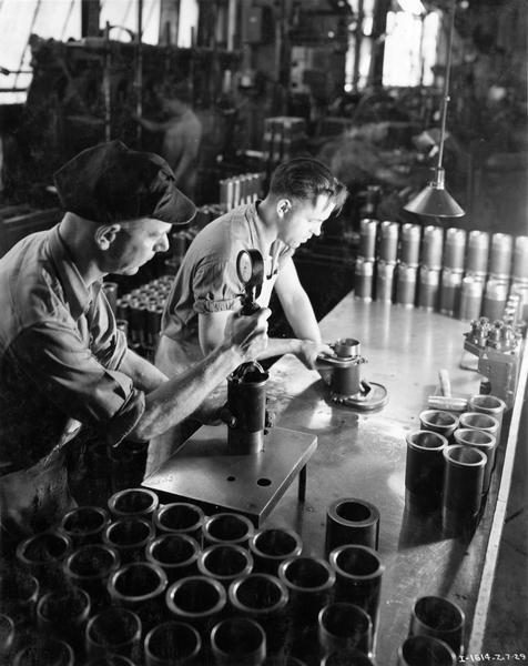 Factory workers inspecting cylinders for Farmall F-12 tractors at International Harvester's Tractor Works.