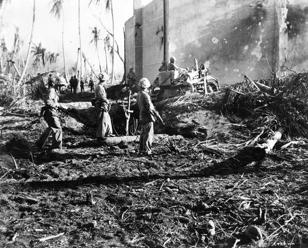 U.S. Marines searching for Japanese soldiers with an International TD-9 Diesel TracTracTor (crawler tractor) and bulldozer on Namur, Kwajalein Atoll, Marshall Islands. Original caption reads: "The Jap pill boxes were buried so well only a bulldozer could rout them out."