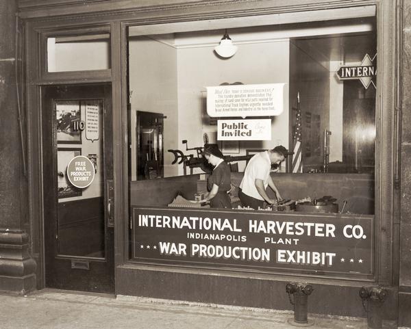Storefront war products exhibit at International Harvester's Indianapolis Works. A sign on the window reads: "Mud pies. Today is serious business! This foundry operation demonstrates the making of sand cores for vital parts required for International truck engines urgently needed by our armed forces and industry on the home front."