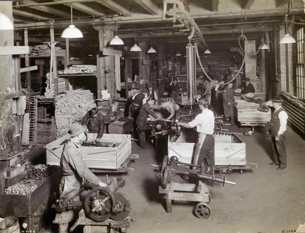 Workers assembling and boxing mower frames for shipment at one of International Harvester's "Harvester Works" (most likely McCormick Works).