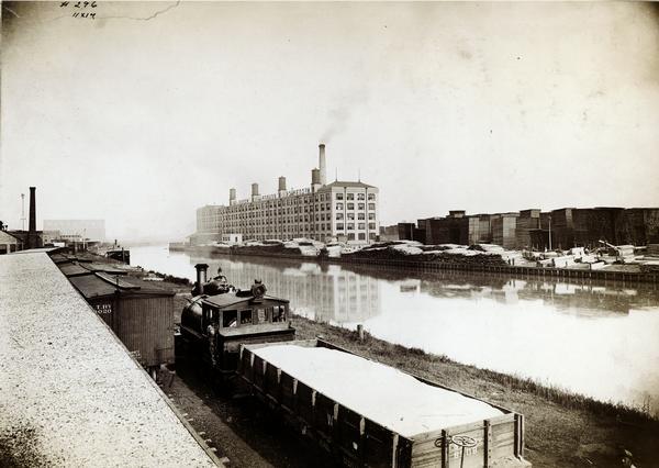 Elevated view of lumberyard at International Harvester's McCormick Works as seen from across the water. The original caption reads as follows: "We think of farm machines as made essentially of steel and iron, and yet surrounding this wood shop at McCormick Works are 39 acres of lumberyard, in which is stored more than 50,000,000 feet of lumber, all of it being thoroughly air-dried before used." McCormick Works was located at Blue Island Avenue and Western Avenue in the Chicago subdivision called "Canalport." The factory was owned by the McCormick Harvesting Machine company before 1902.