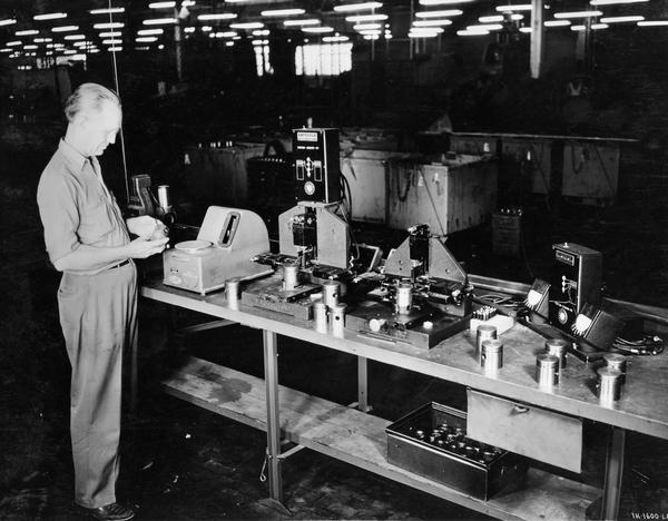 Worker checking dimensions and weight of Farmall Cub pistons at International Harvester's Louisville Works.