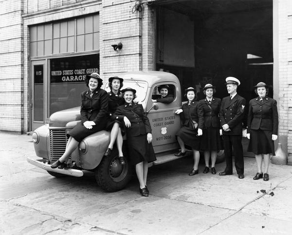 Female members of the U.S. Coast Guard posing with a male officer and an International K-1 truck outside a garage. The Coast Guard had many International trucks in its fleet, used most often to patrol the beaches along the Atlantic and Pacific oceans.