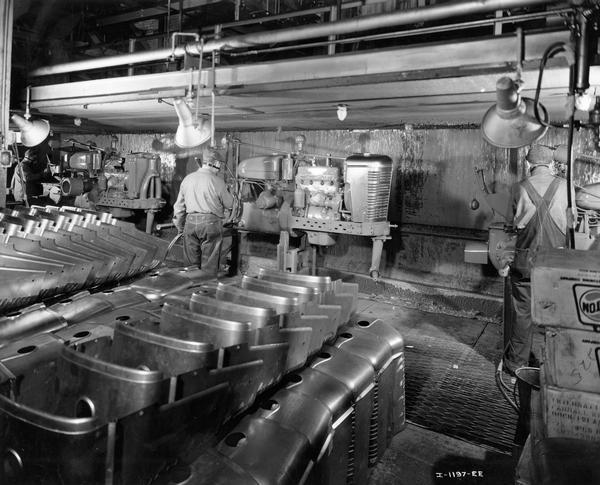 Factory workers painting Farmall tractors in a paint booth at International Harvester's Farmall Works.