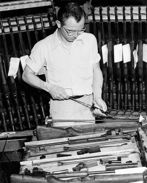 Factory worker inspecting the barrel of an M-1 rifle produced at International Harvester's Evansville Works for the U.S. military.