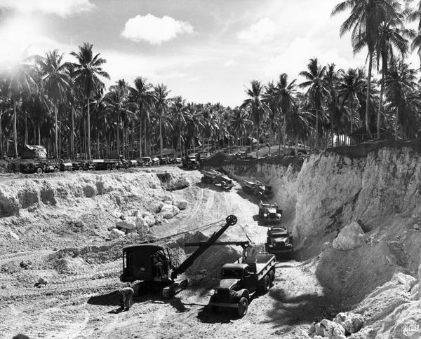 U.S. Marine Corps engineers excavating sand and rock with a steam shovel and a fleet of International trucks in the Pavuvu Islands. The International Harvester trucks include the M-5-H6 (no top) and M-2-4 (4x4 at left).