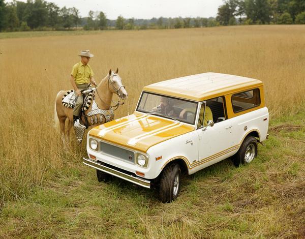 Elevated view of a man and woman sitting in an International Scout Comanche parked in a field. They are talking to a man sitting on a horse. The Comanche was a version of the Scout 800B and was produced in late 1970 and early 1971.