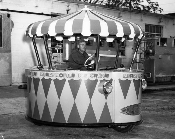 Man driving Merrymobile ice cream vending truck. Press release caption reads: "Merrymobile - colorful ice cream vending vehicle - built by Merrymobile Co., Memphis, Tennessee. Unit is powered by International UC-60 LP-Gas engine. Twenty-one International-powered Merrymobiles have been built, with 100 more on tap."