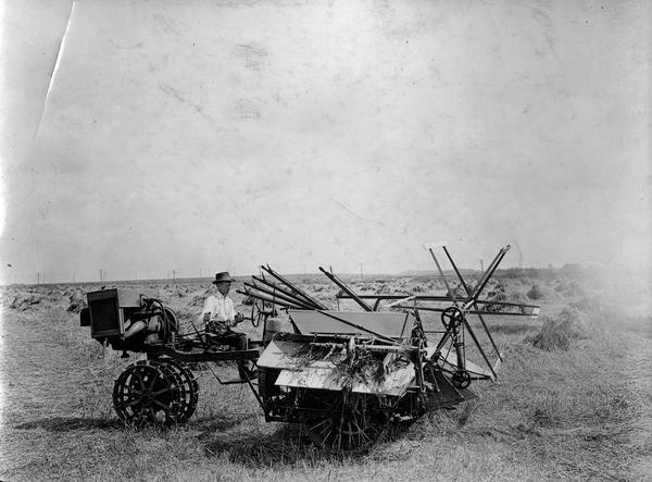 Man operating an experimental McCormick motor-driven grain binder in a field.