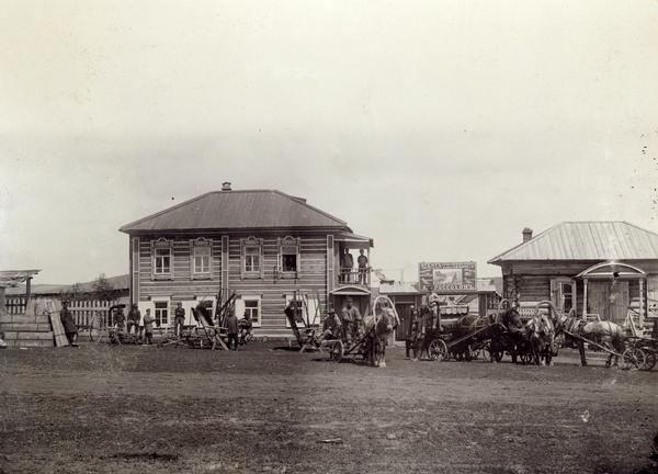 Men, horses, and farm machines in front of an International Harvester dealership in Russia owned by "Rossokhin." Machines include reapers, mowers and a hay rake. A sign bears the "Osborne" brand name.