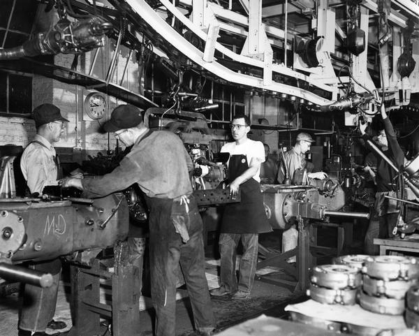 Factory workers on the assembly line at International Harvester's Farmall Works. The men are working on Farmall tractors.