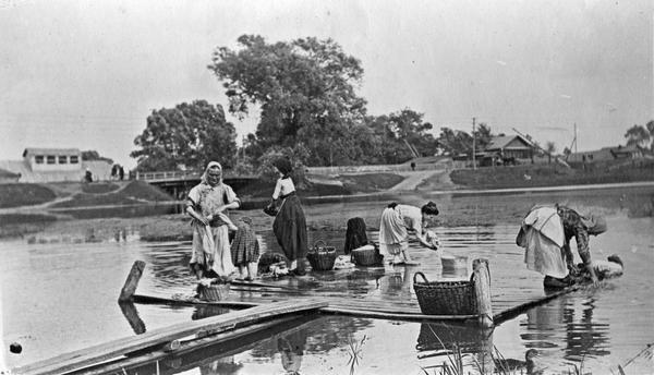 Group of women washing clothes by hand on a pier in a river in Russia. The scene may be near Lubertzy.