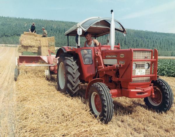 Color photograph of German farmers baling hay with an International 624 tractor built in Germany. The photograph was taken in the Grevenbroich area.