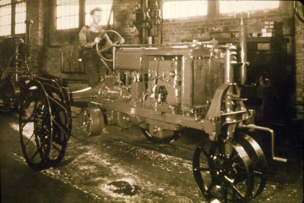 Factory worker driving a Farmall Regular tractor, most likely at Farmall Works in Rock Island.