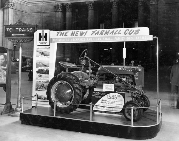 Farmall Cub tractor on display at Union Station. Signs advertise: "The New! Farmall Cub; Designed to Mechanize America's Small, Family-Size Farms," and includes the price of the tractor.