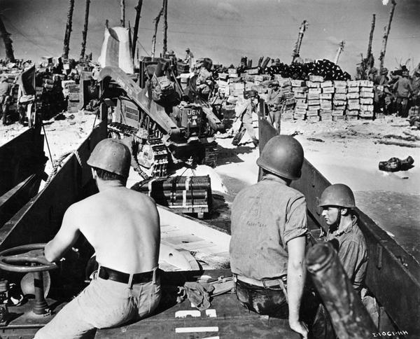 Soldiers, supplies and an International TD-9 diesel crawler tractor (TracTracTor) on a beach at Eniwetok Atoll in the Marshall Islands during World War II.  The original caption reads:  "COAST GUARD POURS SUPPLIES INTO ENIWETOK----Mountains of supplies rise on the beaches of Eniwetok Atoll in the Marshalls from landing craft operated by Coast Guard invaders.  Here a Navy tractor - an International TD-9 Diesel with a dozer shovel - pulls heavy fighting material down the ramp from a Coast Guard-manned landing craft. From: Public Relations Division, U.S. Coast Guard. Washington, D.C."