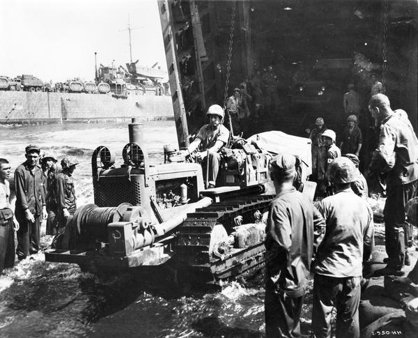 Marine driving an International TD-9 diesel crawler tractor (TracTracTor) off of a landing craft at Cape Gloucester.  The original caption reads:  "When the first waves of Marines hit Cape Gloucester, the engineers moved in with International TD-9 TracTracTors, helped to unload the LST's, and then went to work on construction."