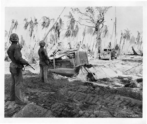 U.S. Marines using an International TD-9 diesel crawler tractor (TracTracTor) and bulldozer on Namur, Kwajalein Atoll during World War II. The original caption reads: "Jap Hunting Bulldozer - Marines use an International TD-9 Diesel and Bulldozer to hunt Japs on Namur, Kwajalein Atoll, when they invaded the Marshalls.  The Jap pillboxes were buried so well only a Bulldozer could route them."