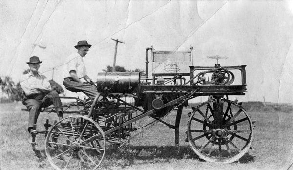 Two men are sitting on an experimental Mogul motor cultivator.
