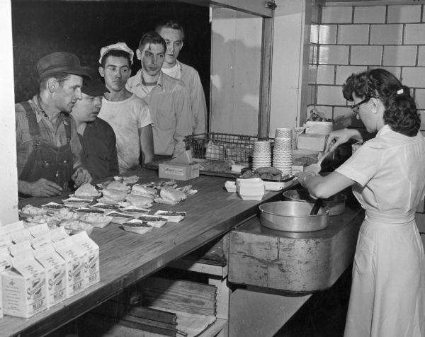 Woman serving meals to factory workers in the cafeteria at International Harvester's Farmall Works.